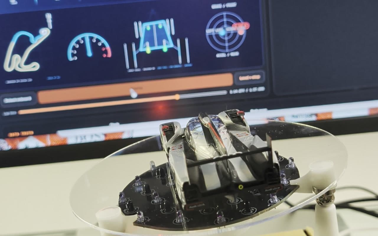 BaBot carrying a model race car while a synchronized chassis telemetry visualizer plays behind it.